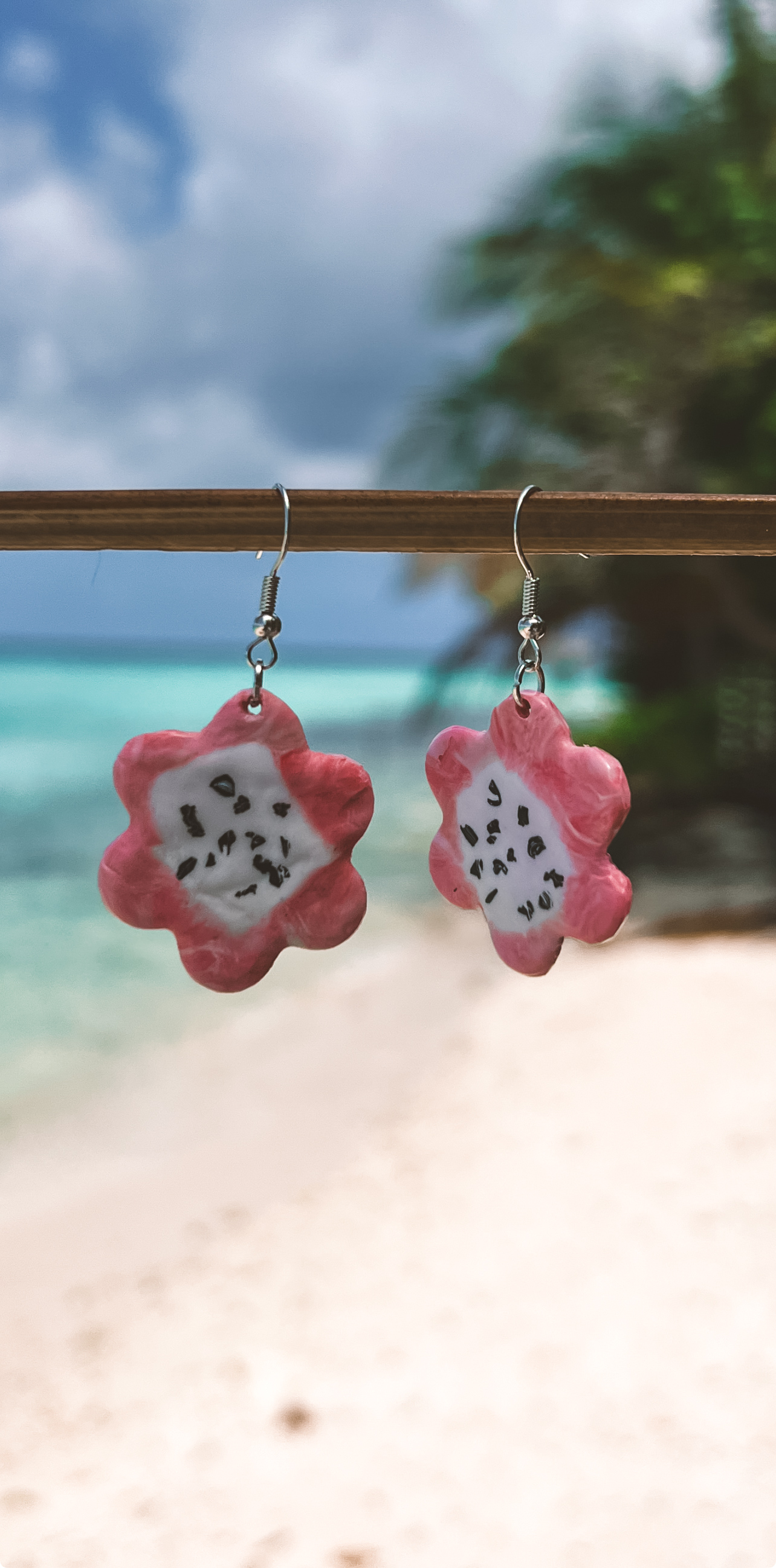 Handmade flower earrings inspired by dragon fruit on a beach