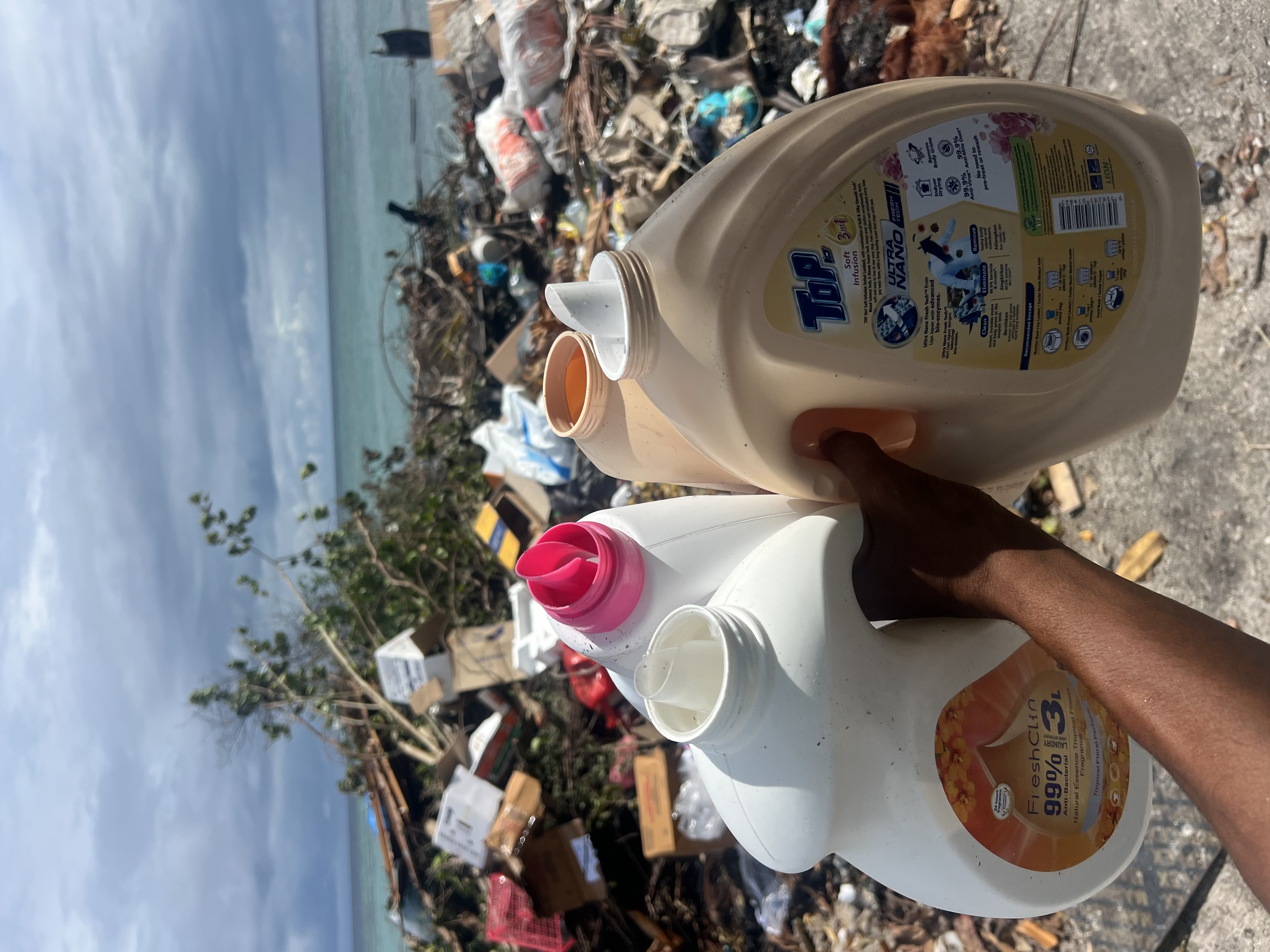 Discarded plastic detergent bottles in the trash, illustrating local waste